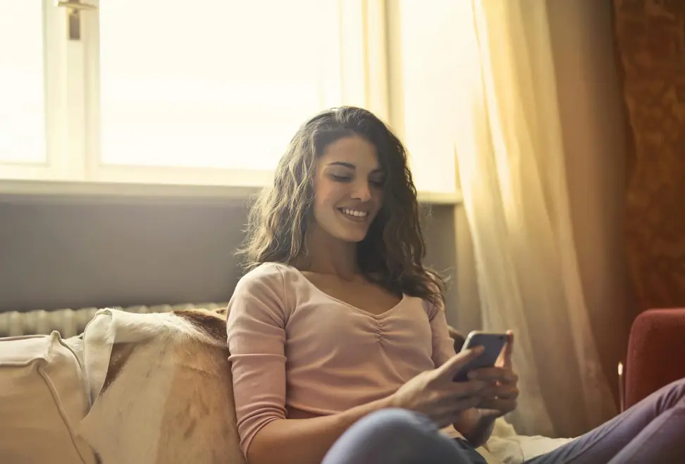 Jovem adulto sorrindo olhando o celular com notificações desligadas