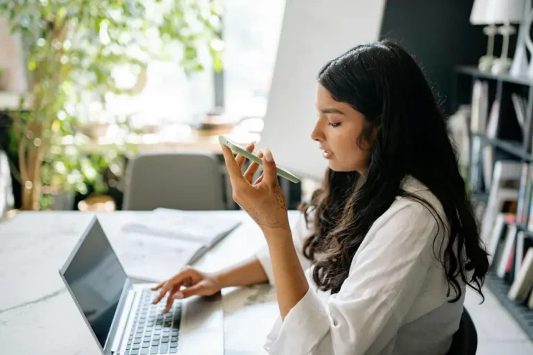 Mulher brasileira usando assistente de voz em seu home office