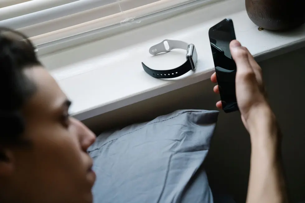 Pessoa adulta usando smartphone, smartwatch e tablet Android em casa iluminada