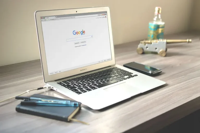 Notebook aberto com Busca Google moderna e plantas em mesa iluminada