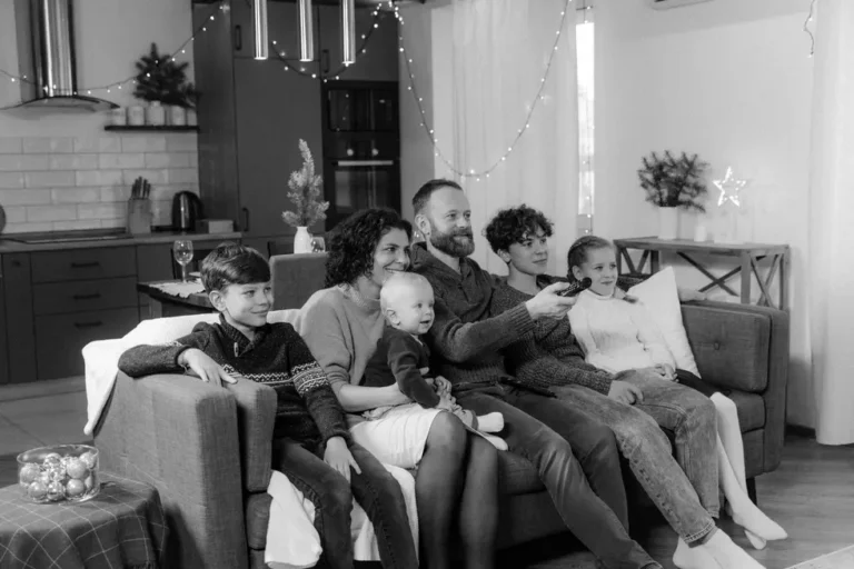 Família brasileira feliz reunida em torno do celular assistindo TV