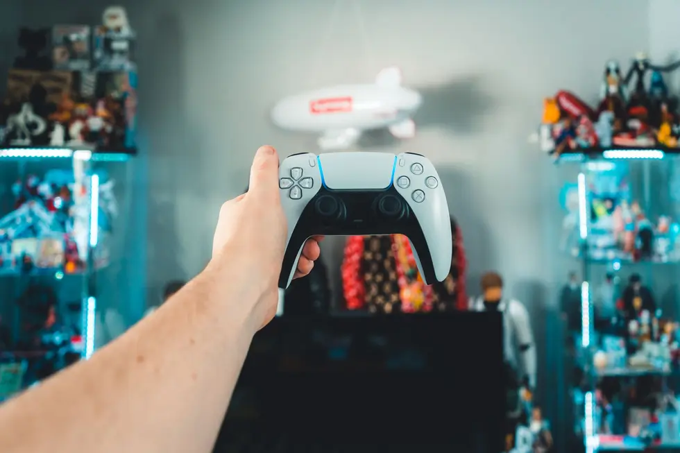 Jogador segurando controle e vitrine de troféus platinum ao fundo