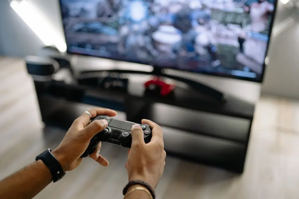 Jogador segurando controle PlayStation em frente à TV com o logo do PS Plus